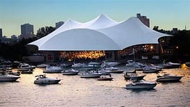 Concert venue by water with boats docked.
