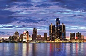 A city skyline with the detroit river in front of it.